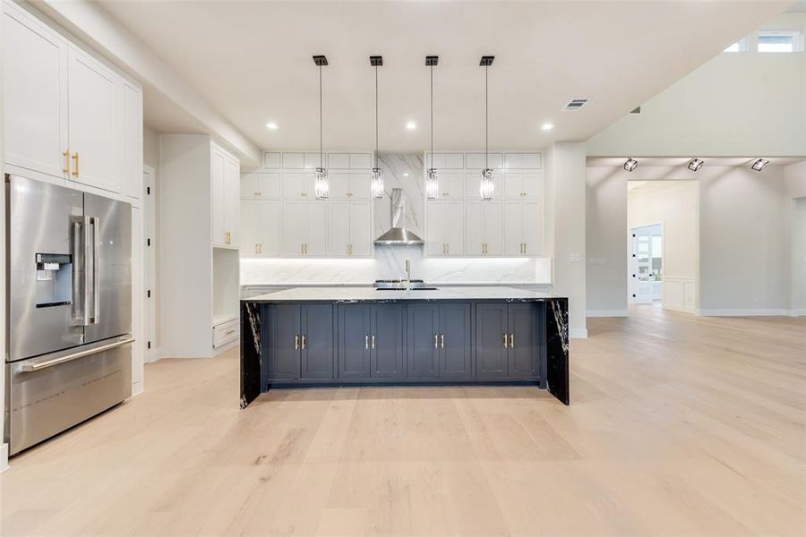 Kitchen with stainless steel fridge, white cabinetry, light wood finished floors, and recessed lighting Kitchen with stainless steel fridge, white cabinetry, light wood finished floors, and recessed lighting