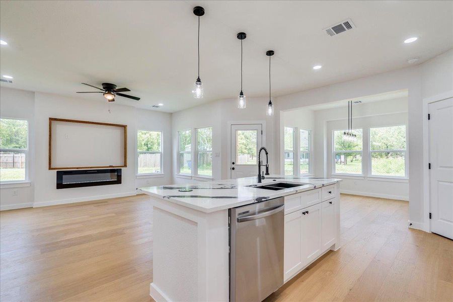 View of the open-concept living space features an elegant kitchen island with modern pendant lighting and rich hardwood flooring.