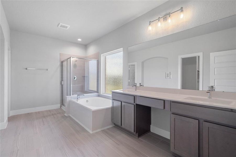 This primary bathroom is definitely move-in ready! Featuring stained cabinets with light countertops, spacious walk-in closet with shelving, high ceilings, custom paint, sleek and dark modern finishes.