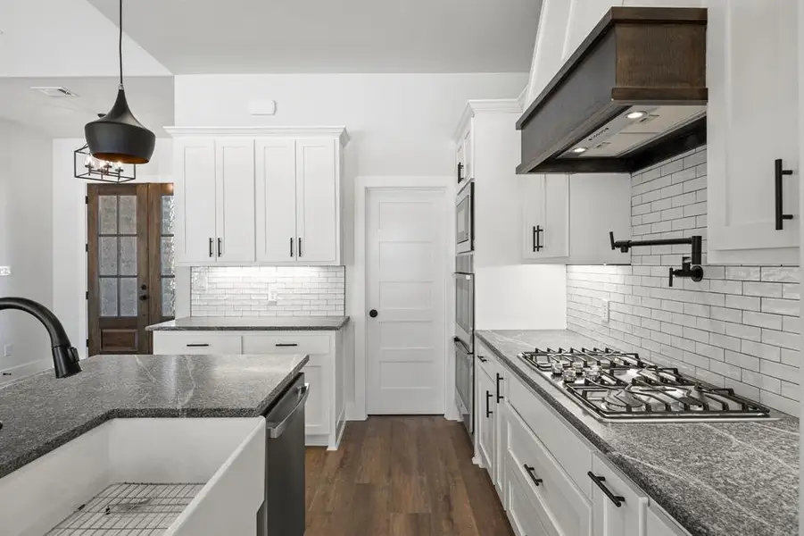 Kitchen with white cabinetry, decorative light fixtures, and dark wood-type flooring