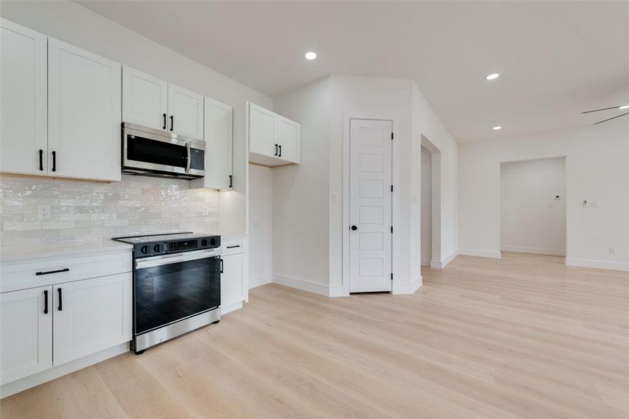 Kitchen featuring electric stove, white cabinetry, light hardwood / wood-style flooring, and decorative backsplash