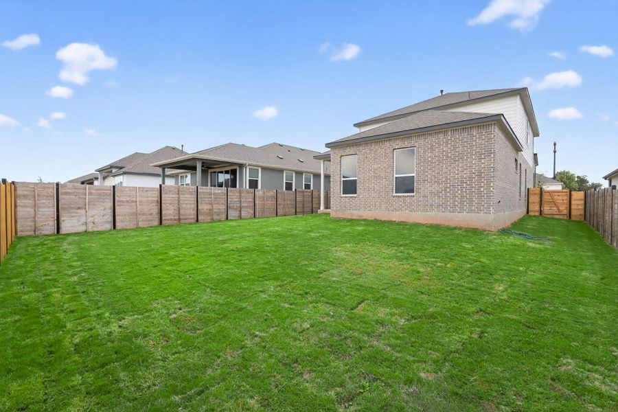 Rear view of property featuring a fenced backyard and brick siding