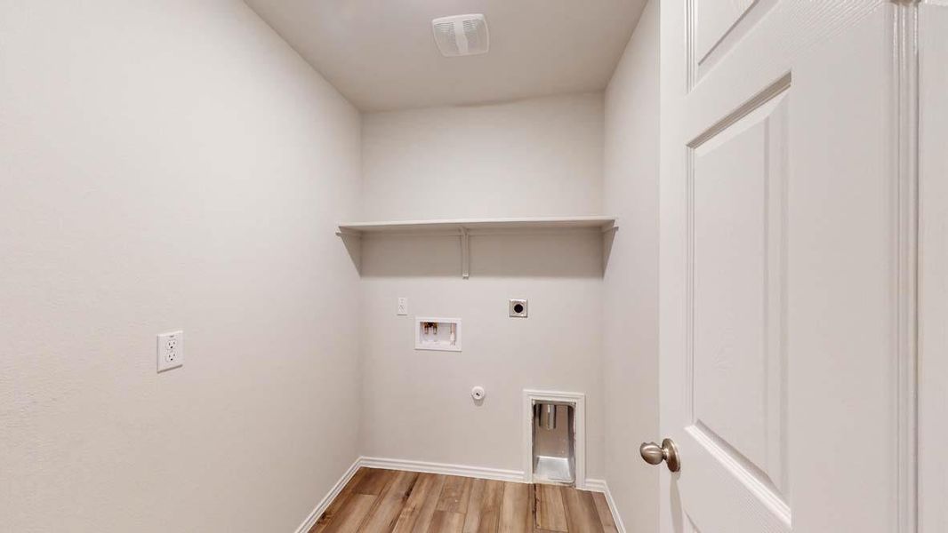 Dedicated laundry room featuring wood-finish flooring and a built-in storage shelf