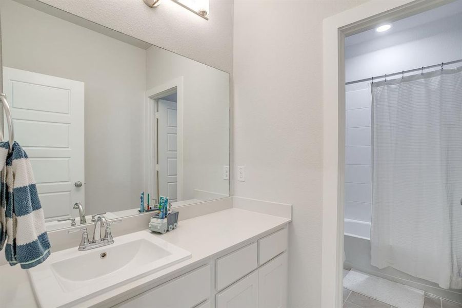 Bathroom with vanity, shower / tub combo with curtain, and light tile patterned floors Bathroom with vanity, shower / tub combo with curtain, and light tile patterned floors