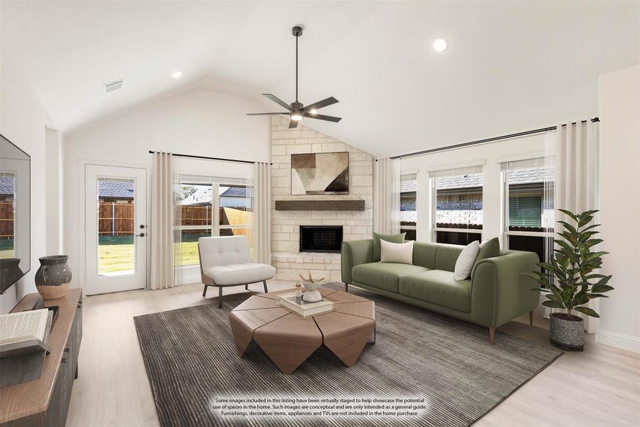 Living room with vaulted ceiling, stone fireplace, ceiling fan, and green sofa on light hardwood floors