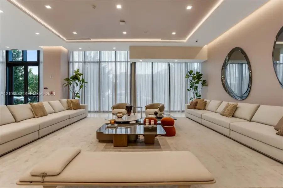 Floor-to-ceiling windows with floor-length drapery, recessed tray ceiling with integrated cove lighting, recessed overhead lighting, and light-toned hard-surface flooring