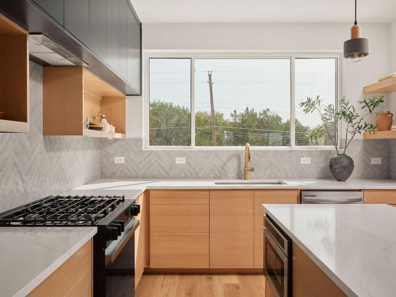 Kitchen featuring open shelves, modern cabinets, appliances with stainless steel finishes, and healthy amount of natural light