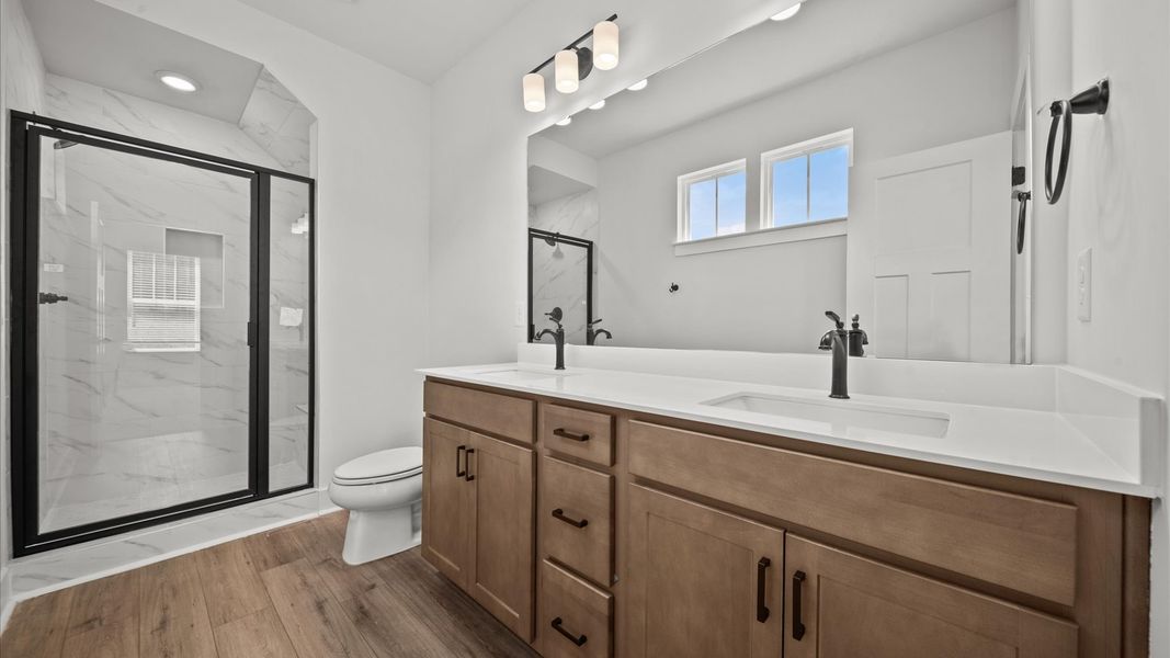 Accomplished design shines in this primary bath with dual vanity and a sleek tiled walk-in shower