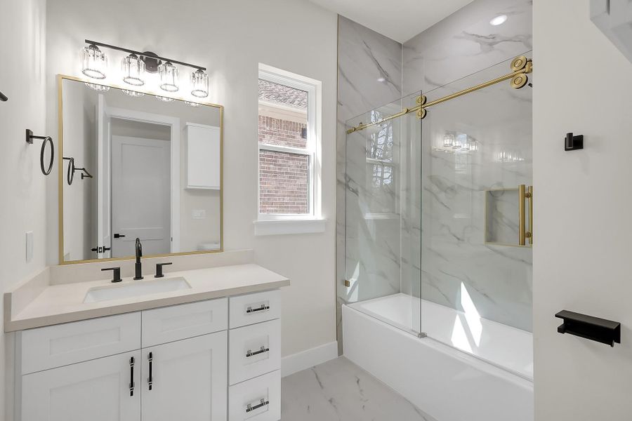 En-suite bathroom for secondary bedroom 1 with glassed in shower/tub combo.