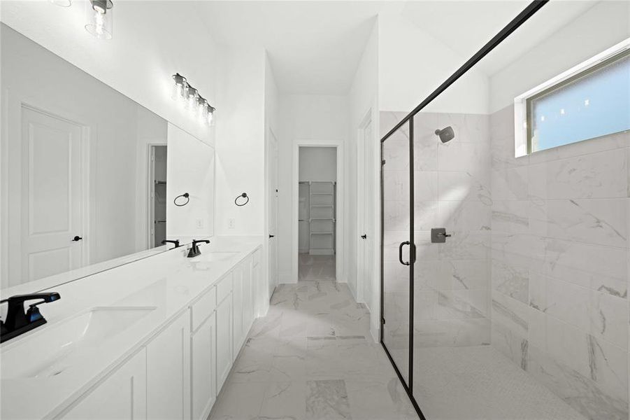 Bathroom with a shower stall, light marble finish flooring, double vanity, and a walk in closet Bathroom with a shower stall, light marble finish flooring, double vanity, and a walk in closet