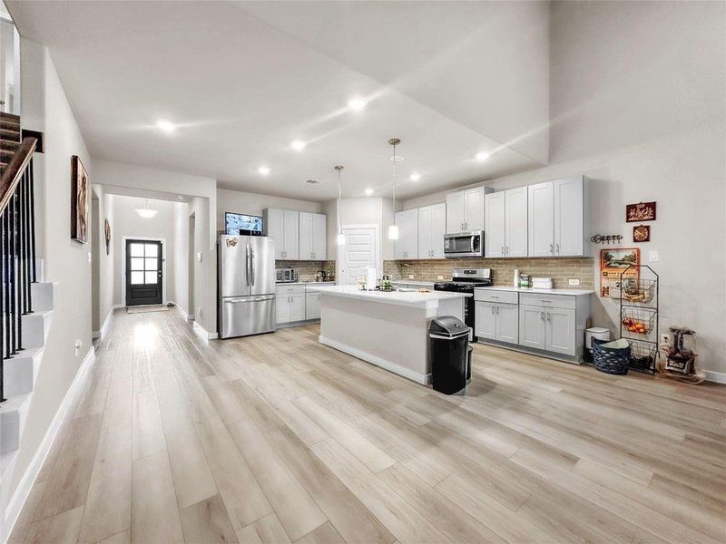 Modern kitchen with a large center island, quartz countertops, stainless steel appliances, ample cabinetry, and contemporary finishes designed for both style and functionality.