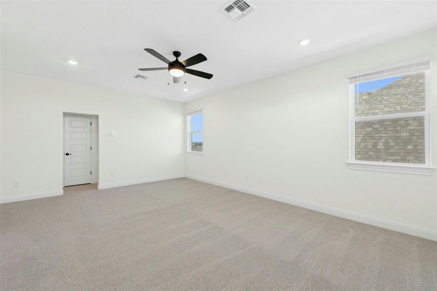 Unfurnished room with light carpet, healthy amount of natural light, recessed lighting, and a ceiling fan