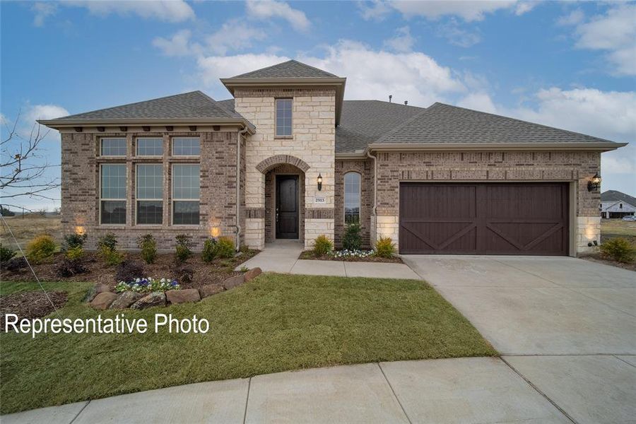 View of front facade featuring a front yard and a garage