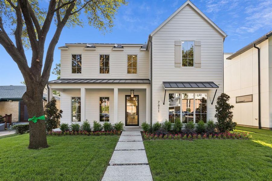 View of front of home featuring a standing seam roof, a metal roof, a front yard, and a porch