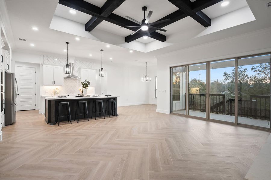 Kitchen featuring dark cabinetry, coffered ceiling, white cabinetry, beamed ceiling, and a kitchen breakfast bar
