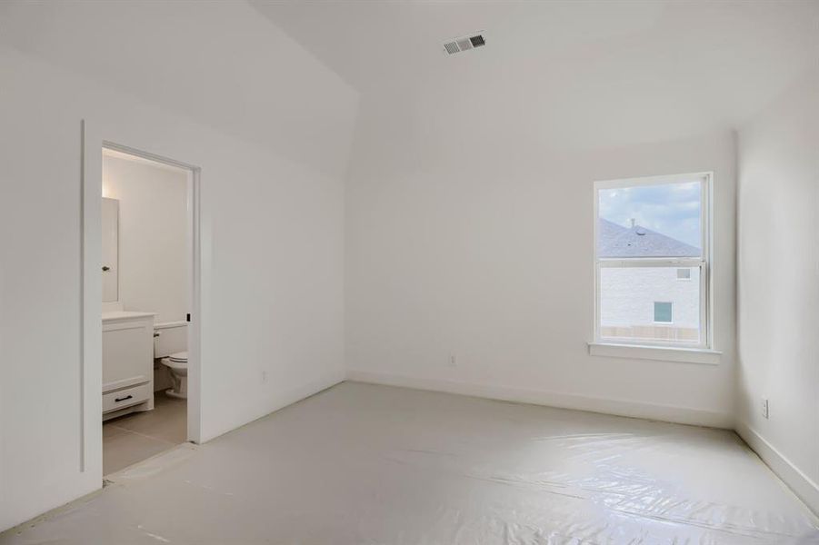 Spacious room with white walls, a single window, and a doorway leading to a bathroom Spacious room with white walls, a single window, and a doorway leading to a bathroom