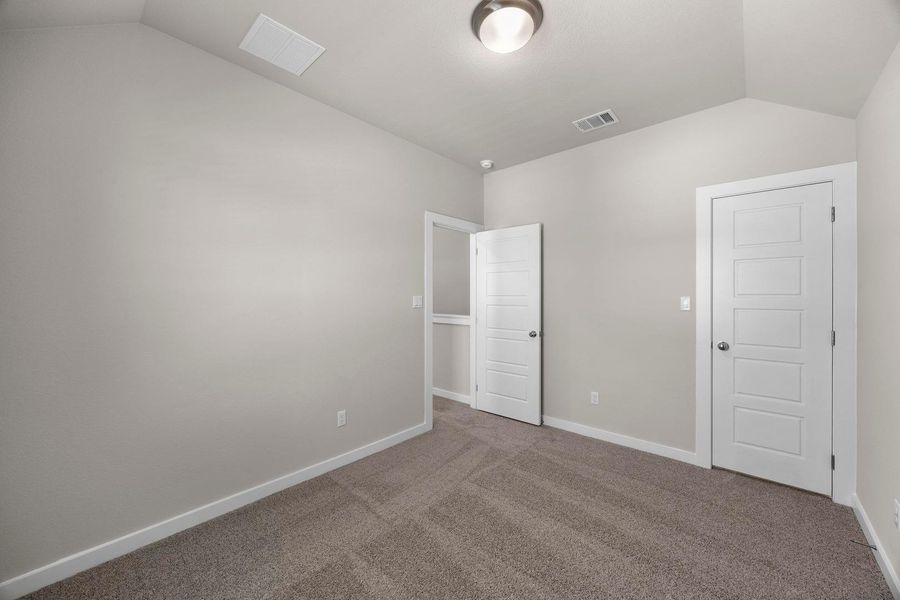 A well-lit bedroom features plush carpeting and classic paneled doors, offering a versatile space. A well-lit bedroom features plush carpeting and classic paneled doors, offering a versatile space.