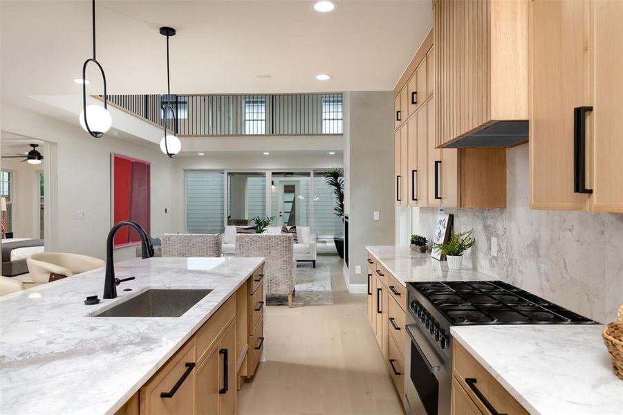 Kitchen featuring gas range, sink, decorative light fixtures, and light brown cabinets