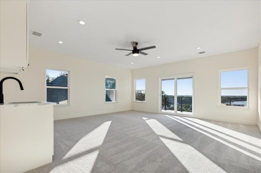 Carpeted living room featuring ceiling fan and sink