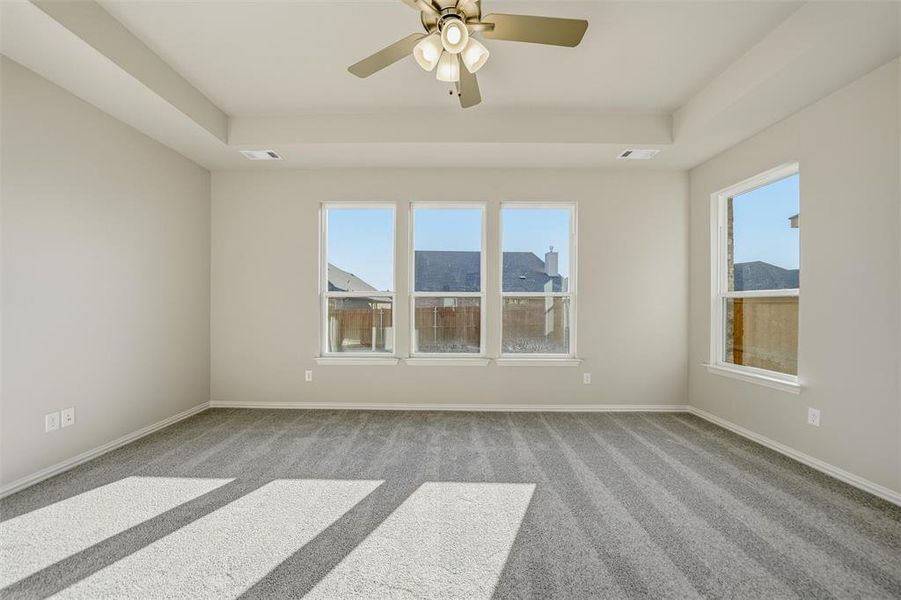 Empty room with a tray ceiling, healthy amount of natural light, and light colored carpet Empty room with a tray ceiling, healthy amount of natural light, and light colored carpet