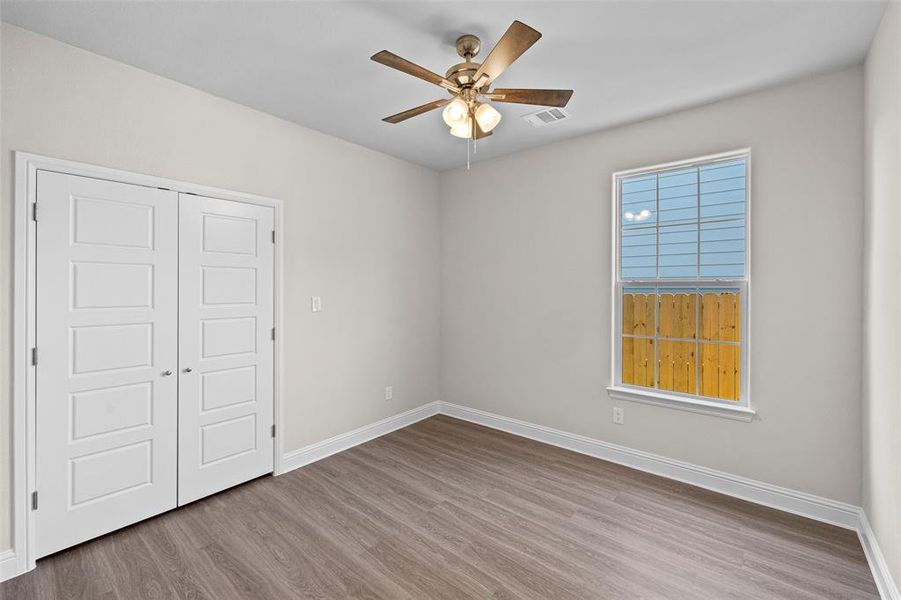 Unfurnished bedroom with light wood-type flooring, ceiling fan, and a closet