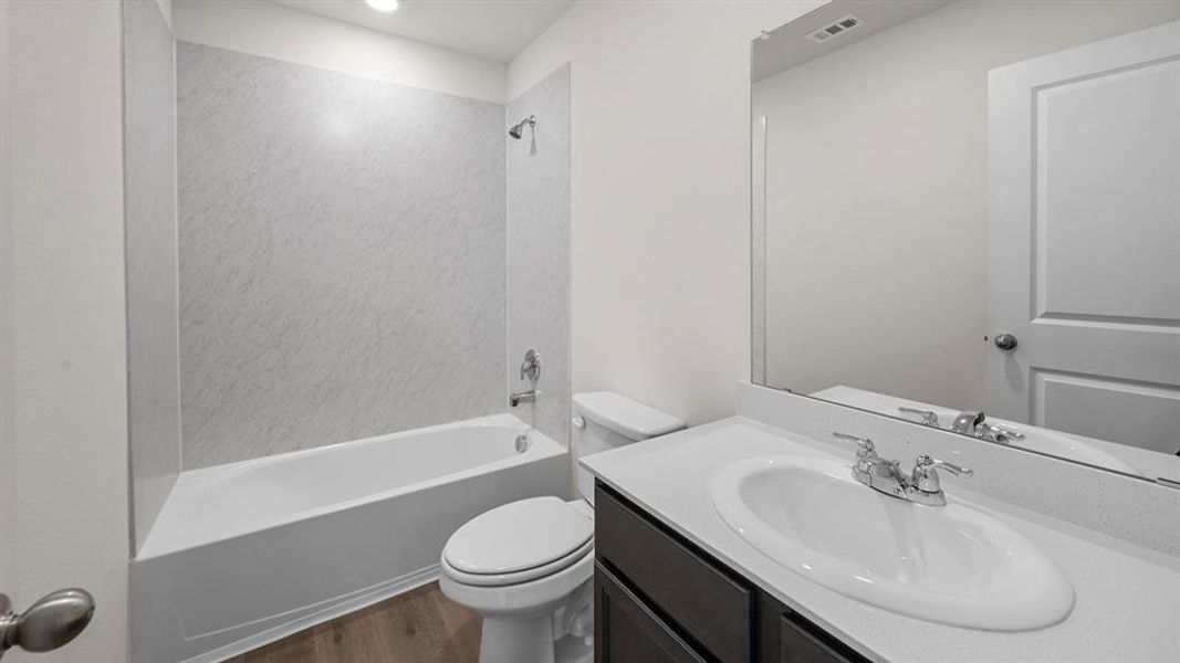 Full bath featuring vanity,  shower combination, and dark wood-type flooring