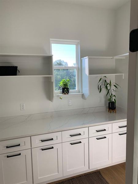 Kitchen featuring light stone countertops, white cabinets, and dark hardwood / wood-style flooring