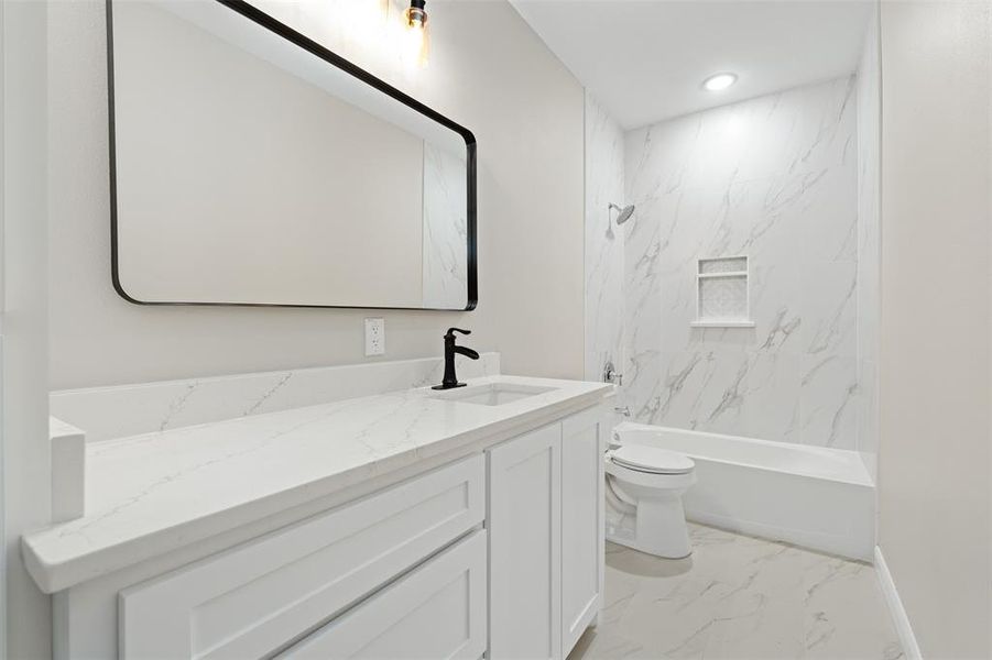Bathroom featuring light marble finish floors, vanity, and shower / bath combination