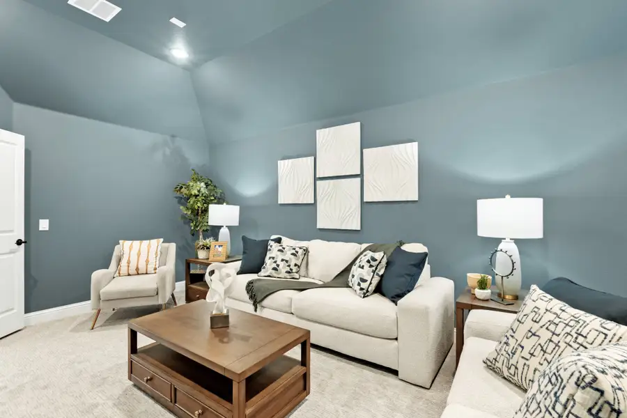 Living room with vaulted ceiling, blue-gray walls, cream sofa, and wood coffee table Living room with vaulted ceiling, blue-gray walls, cream sofa, and wood coffee table