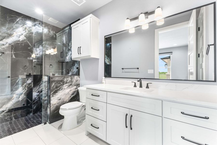 Full bath with toilet, vanity, a marble finish shower, and tile patterned flooring Full bath with toilet, vanity, a marble finish shower, and tile patterned flooring