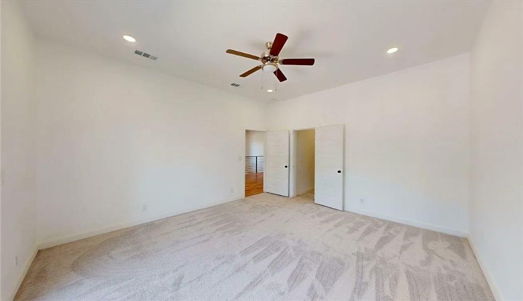 Spacious room featuring vaulted ceilings, light-toned carpeting, and a ceiling fan with integrated lighting