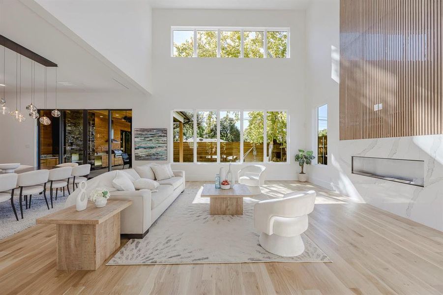 Living area with wood finished floors, a high ceiling, and plenty of natural light Living area with wood finished floors, a high ceiling, and plenty of natural light