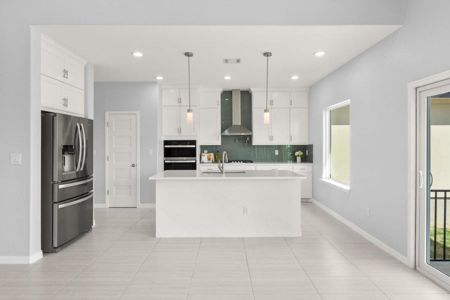 Kitchen featuring stainless steel fridge, wall chimney range hood, light countertops, plenty of natural light, and recessed lighting Kitchen featuring stainless steel fridge, wall chimney range hood, light countertops, plenty of natural light, and recessed lighting