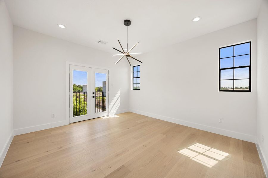 A private primary retreat featuring access to a Juliet balcony, designer lighting, and two windows that fill the space with natural light.