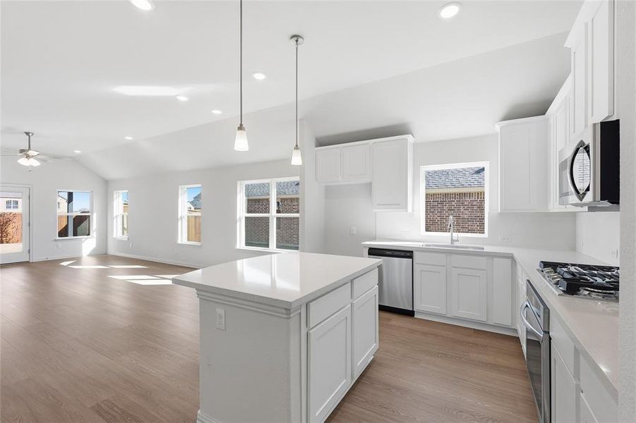 Kitchen featuring white cabinetry, a kitchen island, recessed lighting, lofted ceiling, and light wood-type flooring