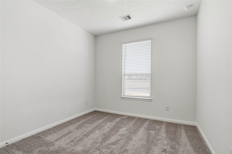 Tucked peacefully in the front of the home is this secondary bedroom. It features plush carpet flooring, a large window with fitted blinds, and an ample sized closet space.