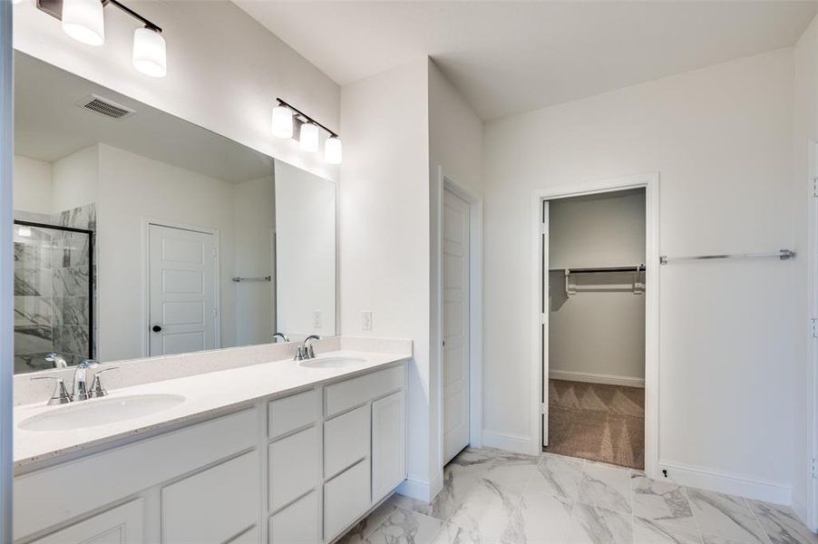 Full bath featuring a shower stall, marble finish flooring, double vanity, and a spacious closet Full bath featuring a shower stall, marble finish flooring, double vanity, and a spacious closet