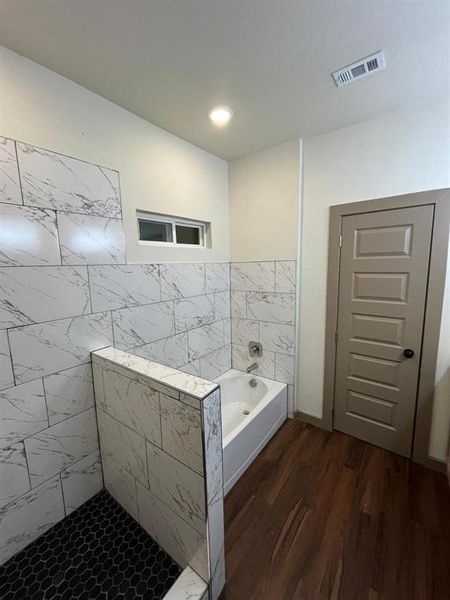 Bathroom featuring a garden tub, dark wood-style flooring, walk in shower, and tile walls Bathroom featuring a garden tub, dark wood-style flooring, walk in shower, and tile walls