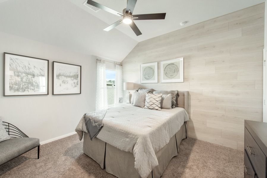 Bedroom with vaulted ceiling, ceiling fan, wood plank accent wall, and neutral carpet