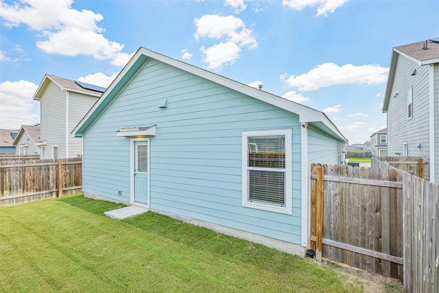 Rear exterior featuring light blue horizontal siding and a white-trimmed window with blinds Rear exterior featuring light blue horizontal siding and a white-trimmed window with blinds
