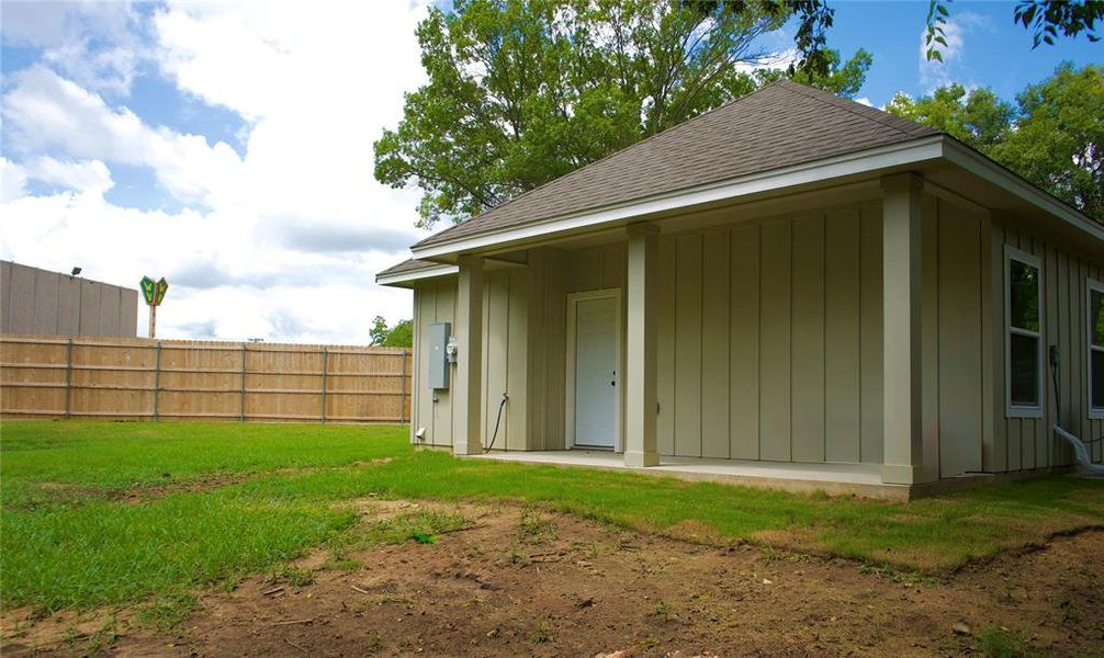 Back of house with board and batten siding and a shingled roof
