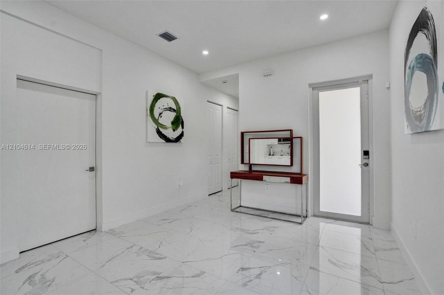Polished tile flooring, recessed lighting, and white walls create a bright interior