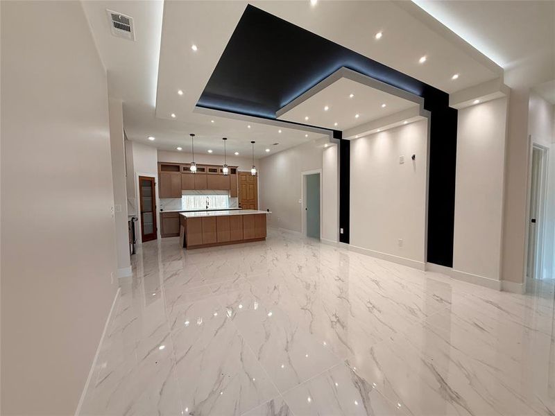 Unfurnished living room featuring baseboards, a tray ceiling, recessed lighting, and light marble finish flooring