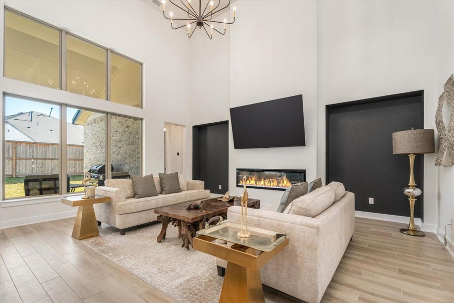 This living room features a modern design with high ceilings and large windows for natural light. It includes a sleek fireplace, mounted TV, and elegant furnishings, creating a cozy yet sophisticated atmosphere.