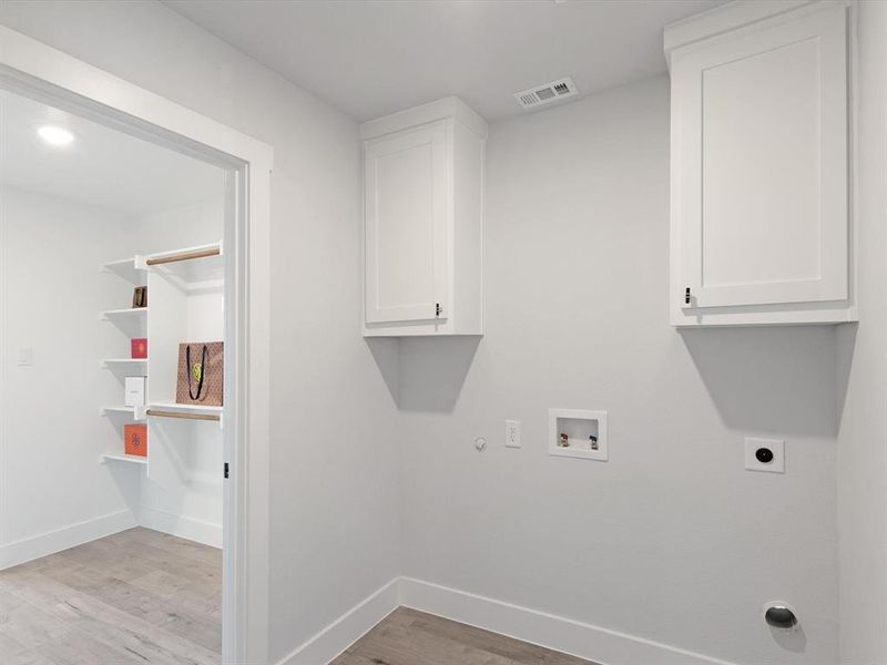 Laundry room featuring gas dryer hookup, hookup for an electric dryer, light wood-type flooring, washer hookup, and cabinets