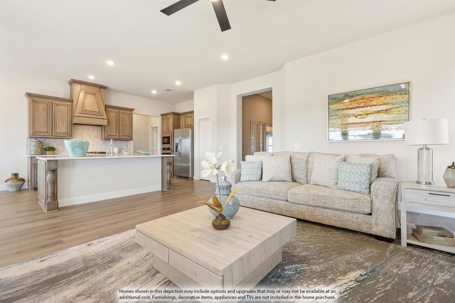 Open-concept living room with beige sofa and wood coffee table, open to kitchen with stainless appliances and wood cabinets Open-concept living room with beige sofa and wood coffee table, open to kitchen with stainless appliances and wood cabinets