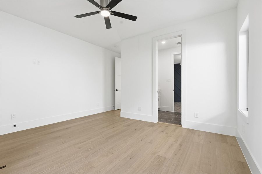 This bedroom offers wide-plank wood flooring, recessed lighting, and a modern ceiling fan with a dedicated ensuite entrance.