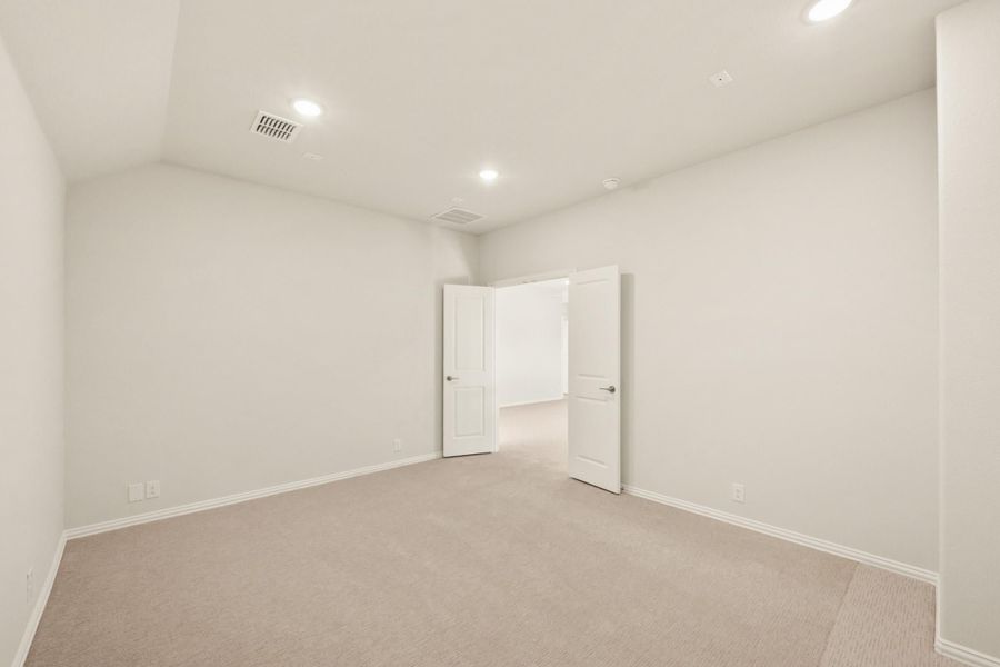 Empty bedroom with beige carpet, white walls, recessed lighting, and two open doors
