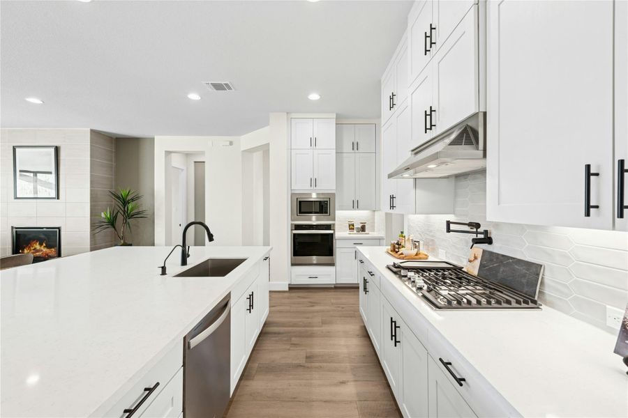 Kitchen featuring recessed lighting, tasteful backsplash, appliances with stainless steel finishes, light stone countertops, and white cabinets Kitchen featuring recessed lighting, tasteful backsplash, appliances with stainless steel finishes, light stone countertops, and white cabinets