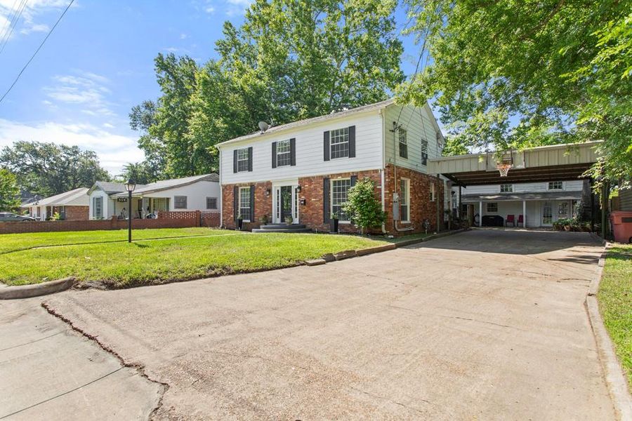 View of front of property with concrete driveway, brick siding, a front lawn, and a carport